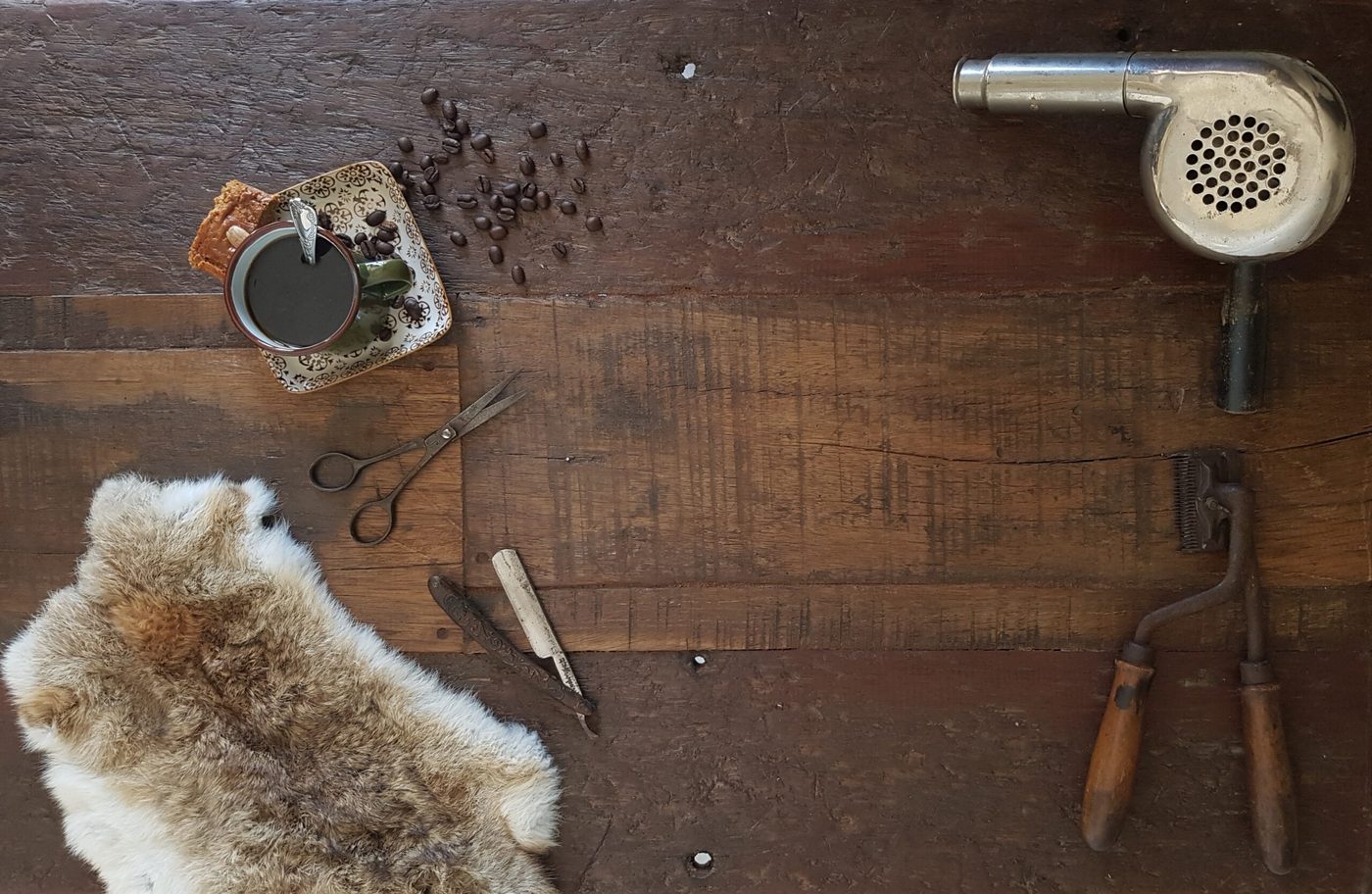 Oud kappersgereedschap op een houten tafel: schaar, scheermes, föhn en tondeuse